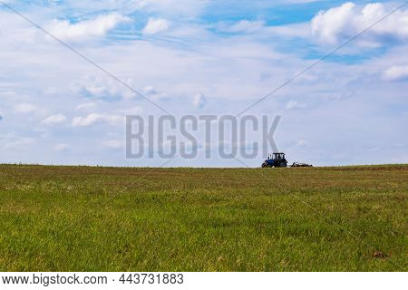 Tractor Working In The Field, Plowing The Land, Preparing For Sowing. View Of The Field And Tractor 