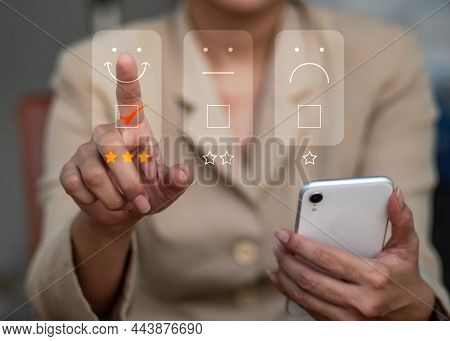 A Lady Picks A Facial Smiling Emoticon On The Virtual Screen. A Survey, Poll, Or Questionnaire Based
