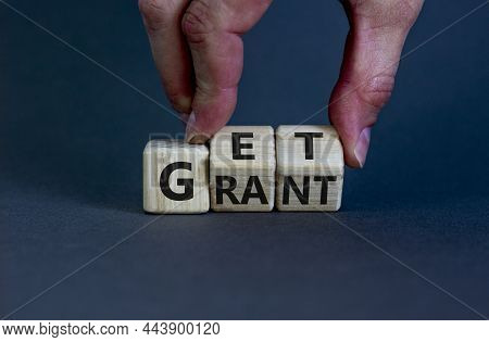 Get Grant Symbol. Businessman Turns Wooden Cubes With Concept Words 'get Grant' On A Beautiful Grey 