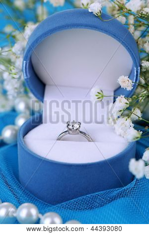 Blomster og forlovelsesring på blå klud