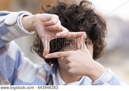 Young Brunette Woman With Curly Hair Making The Framing Sign With Her Hands