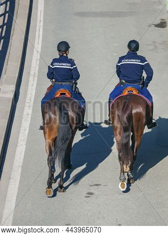Two Riders In Uniform With The Inscription Gendarmerie On The Back Move Around The City On Horseback