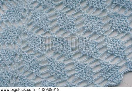 Fragment Of A Knitted Woolen Scarf Close-up. Nice Blue Knitting Pattern, All The Loops Are Visible.