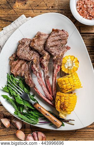 Grilled Lamb Chops Steaks In A Plate With Corn And Tomato. Wooden Background. Top View
