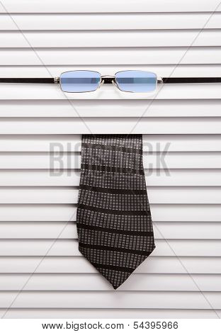 Tie and glasses sticking out of the window blinds