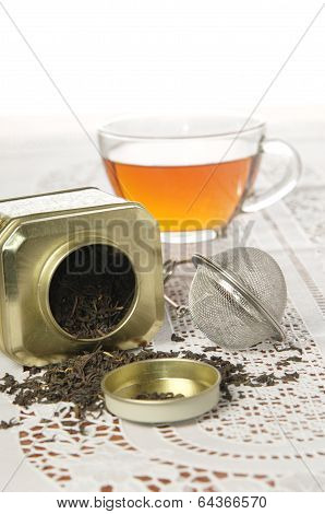 Glass cap of tea and organic black tea in metal can