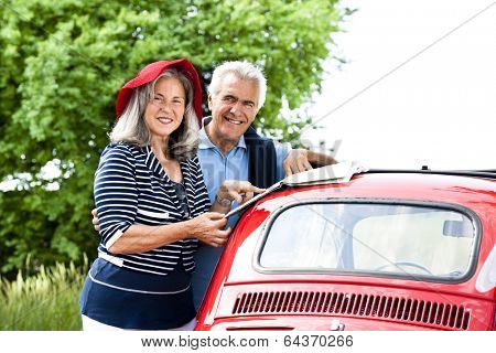 Senior couple with vintage car lookinga t a map