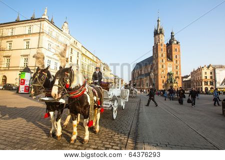 KRAKOW, POLAND - FEB 26, 2014: Carriages at Main Market Square. It dates to the 13th century, and at roughly 40,000 m it is the largest medieval town square in Europe.