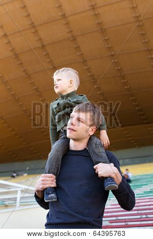 Little boy sit on father's shoulders