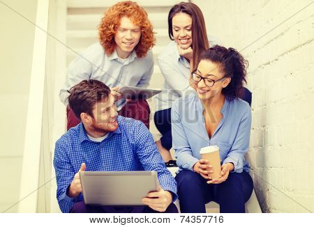 business, technology and startup concept - smiling creative team with laptop and tablet pc computer sitting on staircase