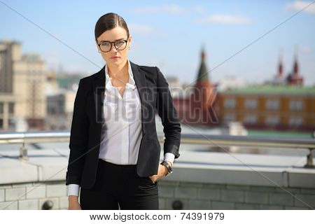 Portrait of beautiful businesswoman in glasses and black pantsuit on terrace overlooking Kremlin