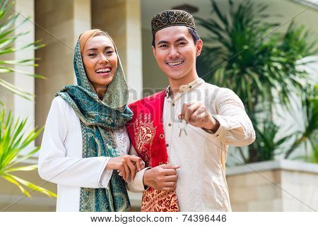 Asian Muslim man and woman moving into house presenting latchkey or key