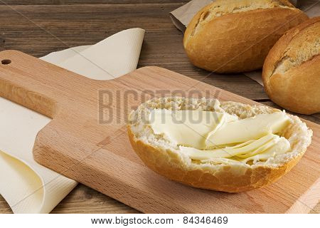 Bun With Butter On A Breakfast Board And Bread Rolls On Old Wood