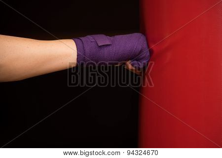 Woman hitting boxing bag, side view