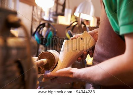 Hands of shoemaker shaping shoe lasts in a workshop