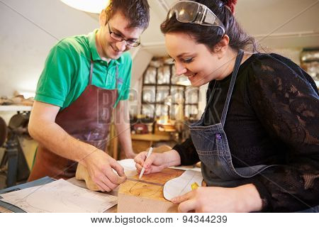 Two young shoemakers preparing shoe lasts in a workshop