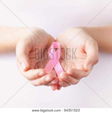 woman`s hands holding pink breast cancer awareness ribbon