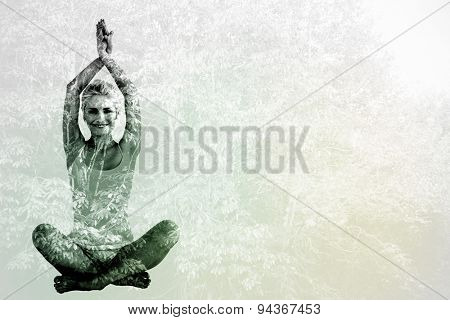 Sporty woman sitting in Namaskar pose with twisted hands against beautiful pink leaved trees
