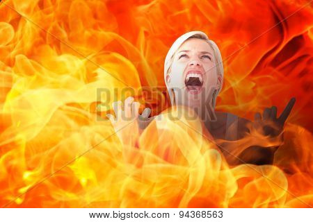 Upset woman screaming with hands up against fire