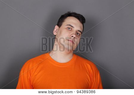 Handsome Young Man Orange T-shirt In Grey Studio Looks At Camera