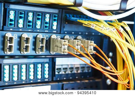 technology equipment with optical fibre cables connected to rack servers in room. Shallow DOF