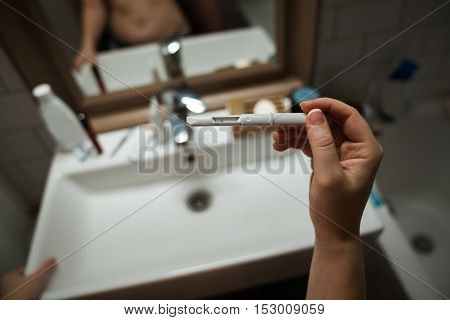 Woman looking at pregnancy test. She's is checking her pregnancy exam. Detail hands of a girl holding pregnancy test. Shallow depth of field with focus on pregnancy test.