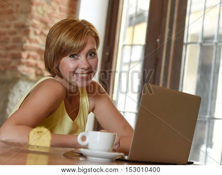 young beautiful and successful woman working or studying at coffee shop with laptop computer and enjoying cup of coffee for breakfast smiling happy and relaxed wifi connected to cafe internet