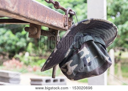 Military camouflage hat hanging on a matal in the forest background