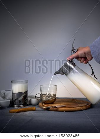 Milk from a jug pouring into glass on old wooden table