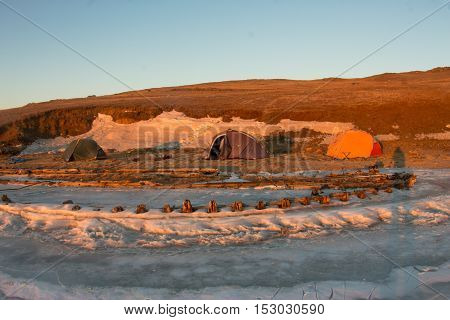 At Dawn Skeleton Of A Ship Frozen In The Ice On The Shore Near The Shore With Tents