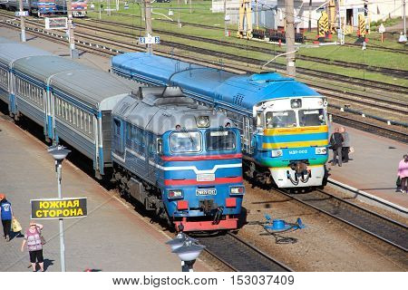 Orsha, Belorussia - Aug 18, 2016: Diesel and electric suburban trains standing on the tracks of the railway station waiting for passengers. Summer evening.