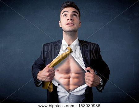 Businessman tearing off his shirt and showing mucular body concept on background