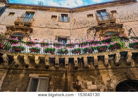 Baroque facede decorated with flowers in Italy. Beautiful travel photo. Colorful background texture with architecture and flowers.