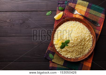 Couscous with mint and lemon in plate on dark rustic table from above. Copy space for text. Flat lay.