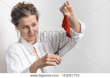 Woman with old scissors and a small piece of red cloth in a white background