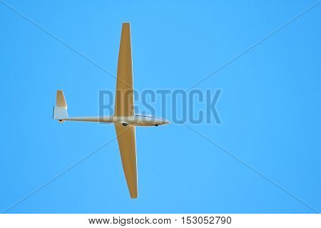 A sailplane in front of a blue sky glides through the air without its own motor drive.