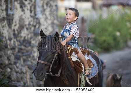 Ushguli Georgia - August 15 2016: Color image of a young boy riding a horse in the Caucasian village of Ushguli Georgia.