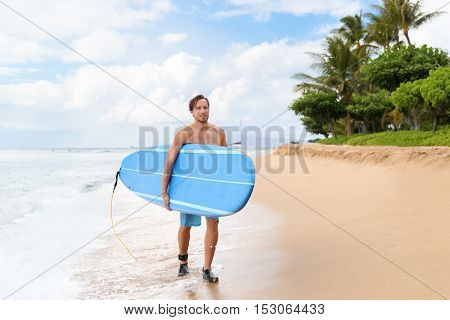 Surfer man surfing on maui beach hawaii, usa. Handsome male athlete walking carrying blue long surfboard going for a surf session on kaanapali beach, hawaiian destination.