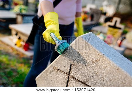 Woman Cleans A Grave With Brush