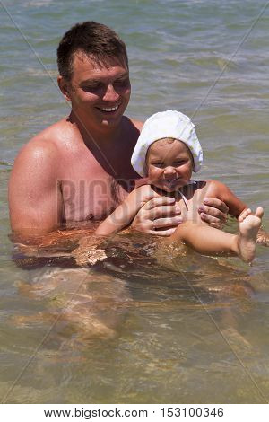 man father and daughter a little girl swimming in the sea in the waves splashing happiness joy laughter summer vacation