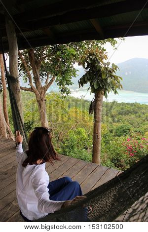 a casual happy woman relaxing on a hammock in the with seaview from a viepoint on Phi-Phi Island Krabbi Thailand