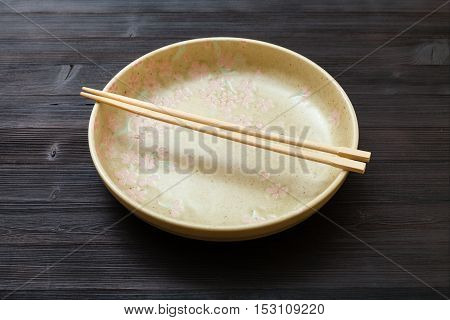 Yellow Plate With Chopsticks On Dark Brown