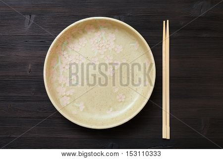 Top View Yellow Plate And Chopsticks On Brown