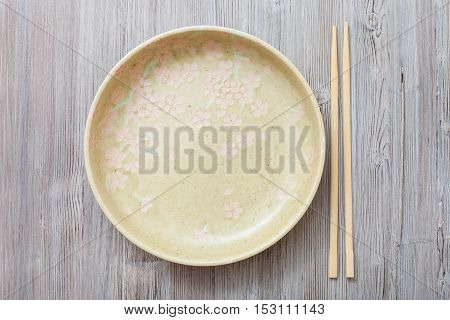 Top View Of Yellow Plate And Chopsticks On Gray
