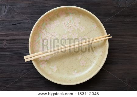Top View Of Yellow Plate With Chopsticks On Brown