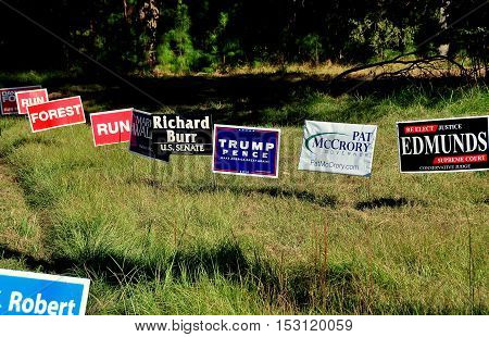 Pittsboro NC - October 23 2016: A row of political advertising campaign signs for both local and national candidates at the intersection of two rural roads