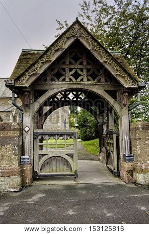 Beautiful elaborate carved stone and wood lychgate entrance to English village Church
