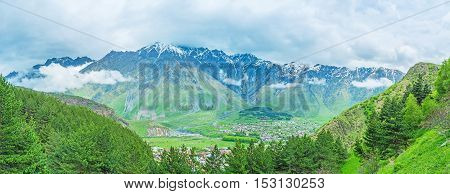 The view on Stepantsminda resort in the mountain valley above the spruces of Kazbegi National Park Georgia.