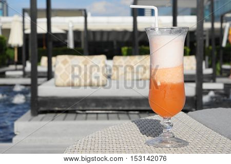 sour orange cocktail with sun bathing bed as background - evening sunlight