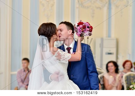 Beauty bride and handsome groom are registering the marriage. Wedding couple is marrying. Beautiful model girl in white dress and in lace veil. Man in suit. Female and male portrait. Cute lady and guy